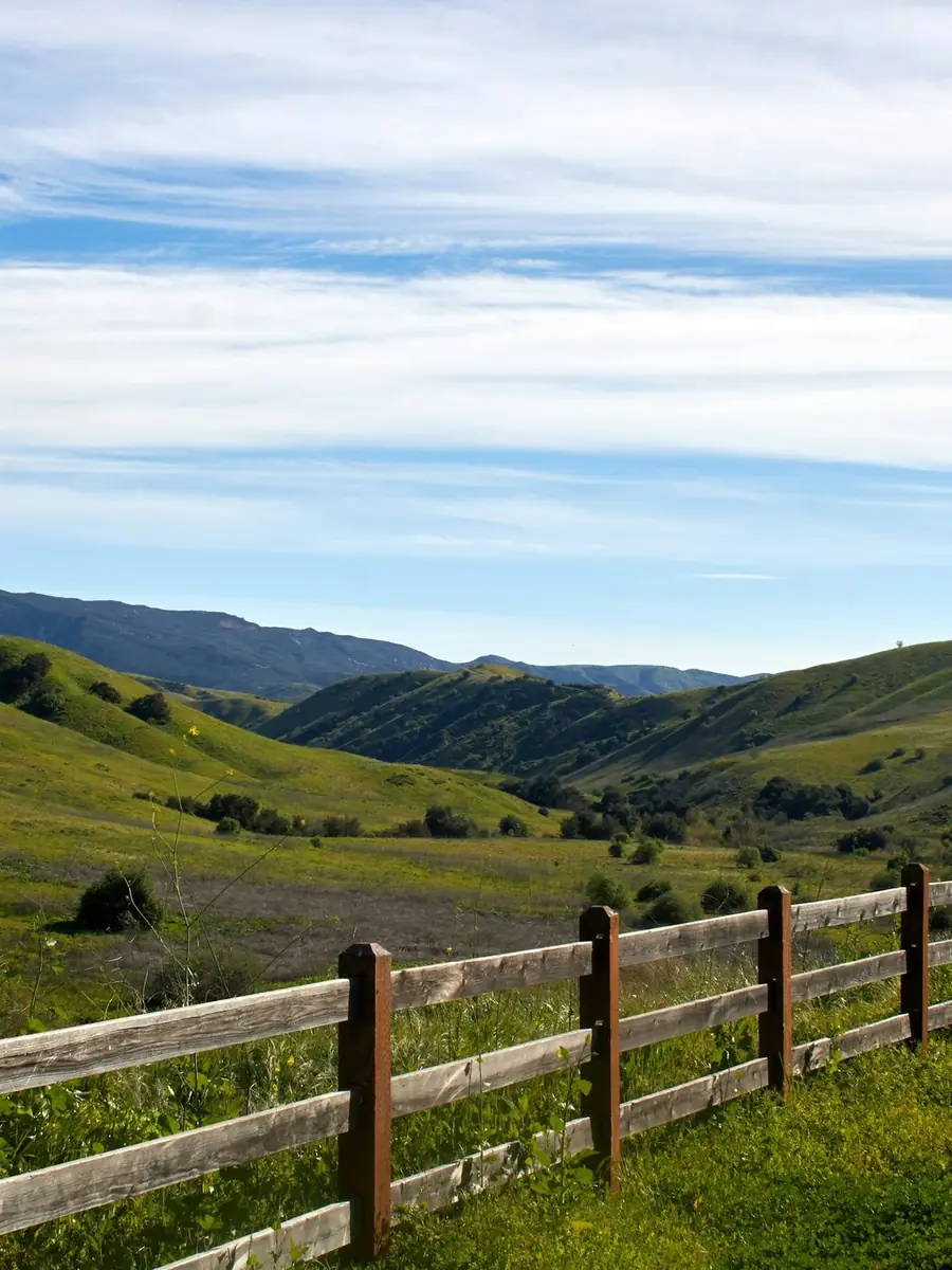 Green rolling hills with a ranch fence near the coast